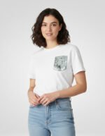 Mujer sonriendo con la camiseta blanca de algodón faaia que tiene un bolsillo de tela fallera en tonos verdes