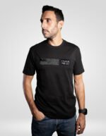 Modelo masculino vistiendo una camiseta negra de algodón marca faaia, con un detalle rectangular de tela fallera negra tono sobre tono en el pecho.