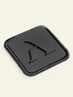 Detalle del parche negro de microinyección con logotipo Faaia en la sudadera blanco coco.