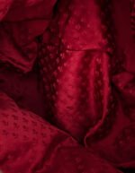 Detalle en primer plano del damasco de seda rojo artesanal utilizado en la capucha de la sudadera Faaia.