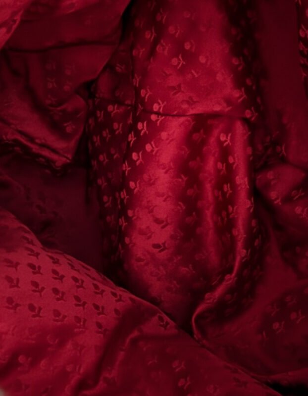 Detalle en primer plano del damasco de seda rojo artesanal utilizado en la capucha de la sudadera Faaia.