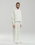 Modelo masculino vistiendo sudadera Faaia en blanco roto con capucha forrada en damasco de seda rojo.