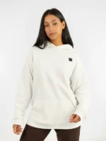 Modelo femenina vistiendo la sudadera Faaia blanco coco con parche y capucha en damasco marrón y rosa.