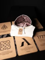 Sudadera blanca con capucha forrada de tela fallera damasco encima de plegador de madera Faaia