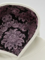 Primer plano del interior de capucha en damasco marrón y rosa de la sudadera Faaia blanco coco.