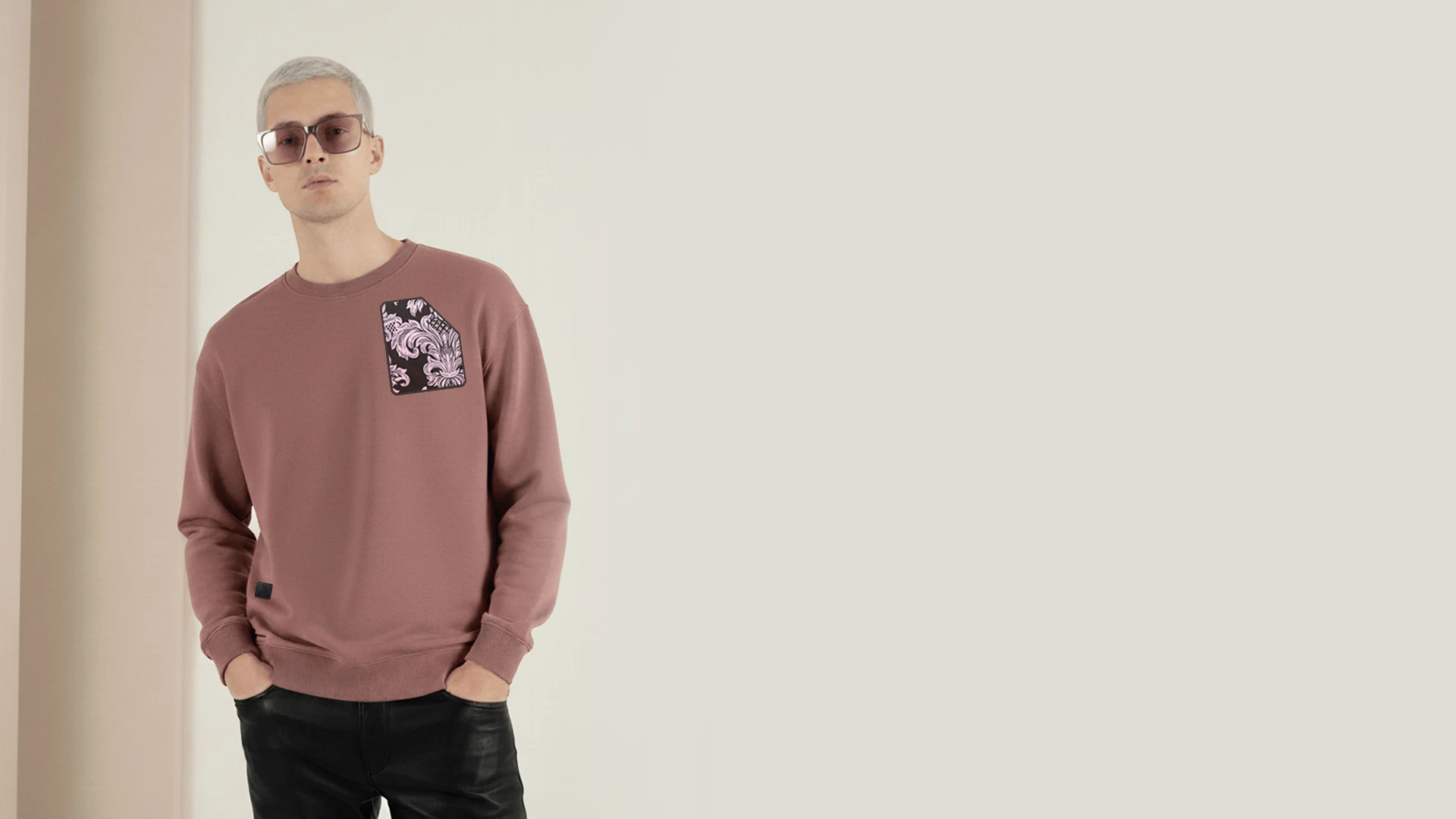 Modelo hombre joven posando con gafas de sol y una sudadera de color burdeos de la marca Faaia.