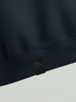 Trozo de tela fallera negra aplicada en el bajo de una sudadera azul marino marca Faaia.