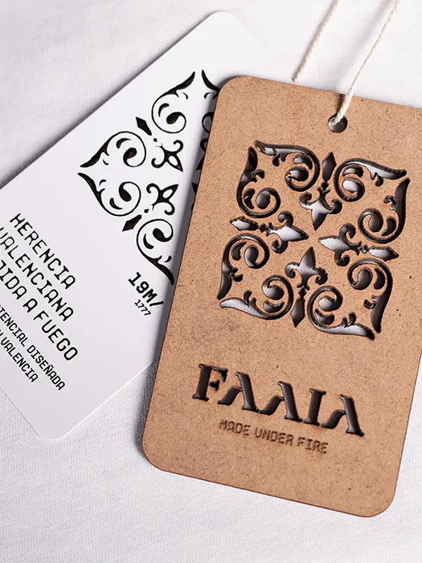 Etiqueta de madera sostenible cortada a fuego y etiqueta de cartón blanco reciclado de la marca Faaia Moda con tela fallera.