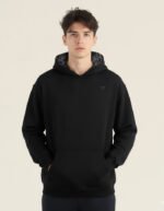 Modelo hombre joven vistiendo una sudadera negra oversize de la marca Faaia con damasco negro en la capucha.
