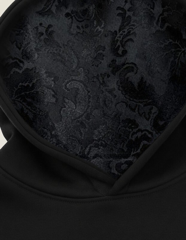 Tela de damasco tejida en telar de Valencia y bordada en el interior de la capucha de una sudadera negra Faaia.