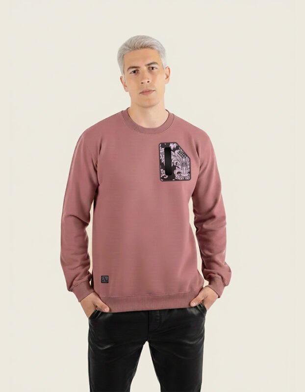 Hombre joven con sudadera de color burdeos de la marca Faaia que lleva un fragmento de damasco como el de las telas falleras en el pecho.