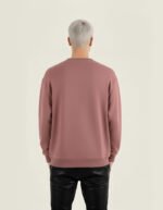 Hombre joven de espaldas que lleva puesta una sudadera de la marca Faaia color burdeos.