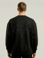 Hombre joven con pelo negro posando de espaldas con una sudadera oversize negra con un bordado exclusivo en la espalda.