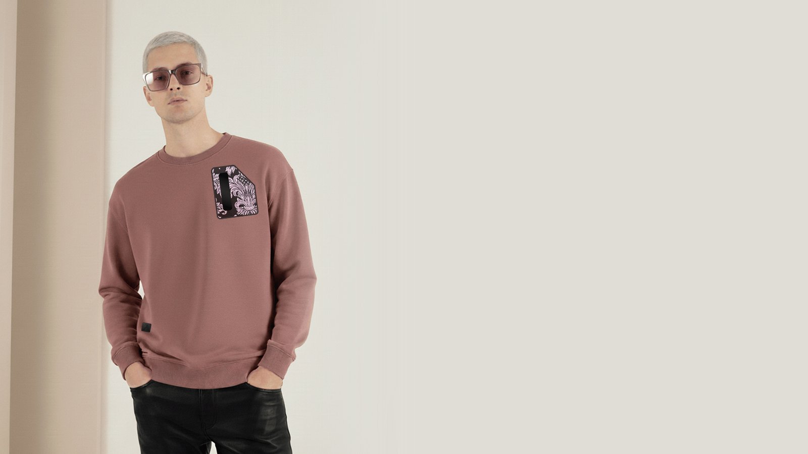 Hombre joven posando con una sudadera de la marca Faaia en color burdeos que lleva tela damasco utilizado en las fallas de Valencia.