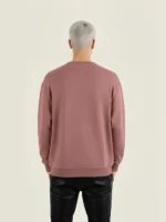 Modelo joven posando con sudadera de la marca Faaia de color burdeos.