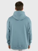 Joven modelo con el pelo negro posando de espaldas con una sudadera Faaia de color citadel.