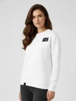 Mujer joven con el pelo oscuro posando de frente con una sudadera blanca marca Faaia.