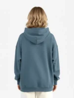 Mujer rubia joven posando de espaldas con sudadera Faaia color citadel.