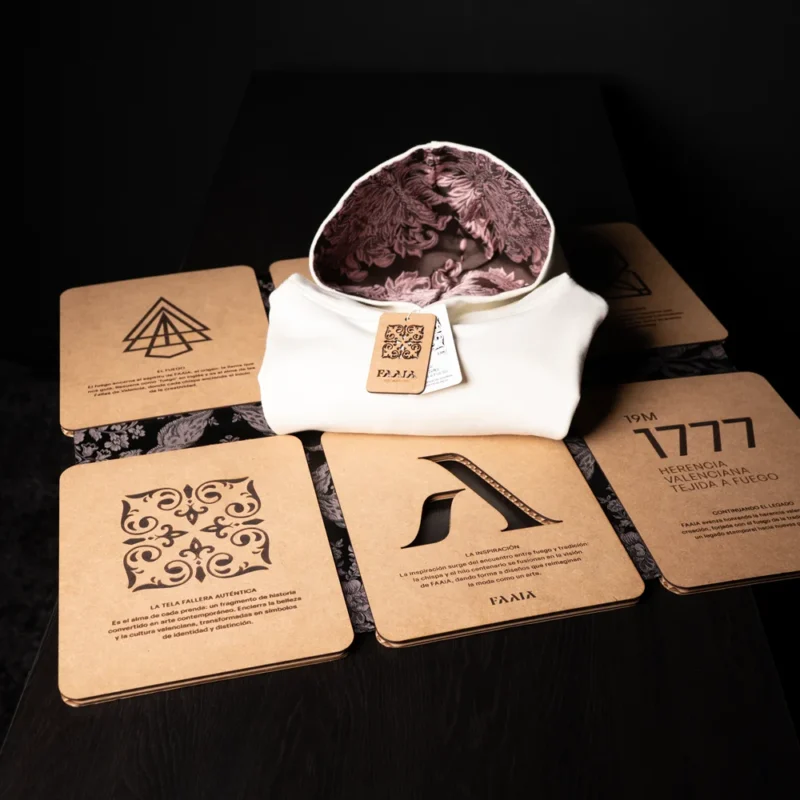 Plegador de ropa Faaia con sudadera blanca con capucha de tela fallera marrón y rosa.