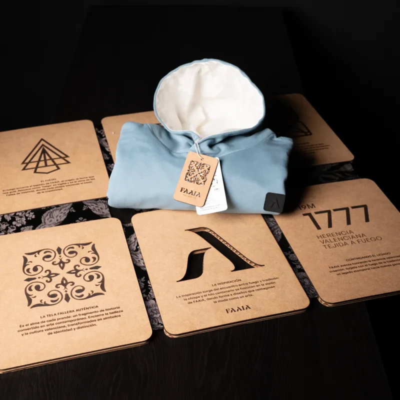 Plegador de madera y sudadera marca Faaia azul con capucha blanca encima