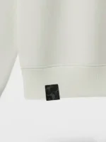 Etiqueta de tela damasco negra aplicada en sudadera de color gray marca Faaia.