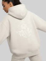 Mujer joven posando con una sudadera de la marca Faaia con un bordado en blanco tono sobre tono.