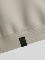 Trozo de tela de valenciana (fallera) brocatel cosido en el bajo de una sudadera color tierra marca Faaia.