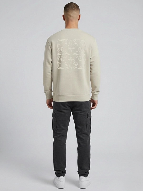 Hombre joven posando de espaldas a la cámara con una sudadera de color tierra que tiene un bordado ornamental al tono de la marca Faaia.