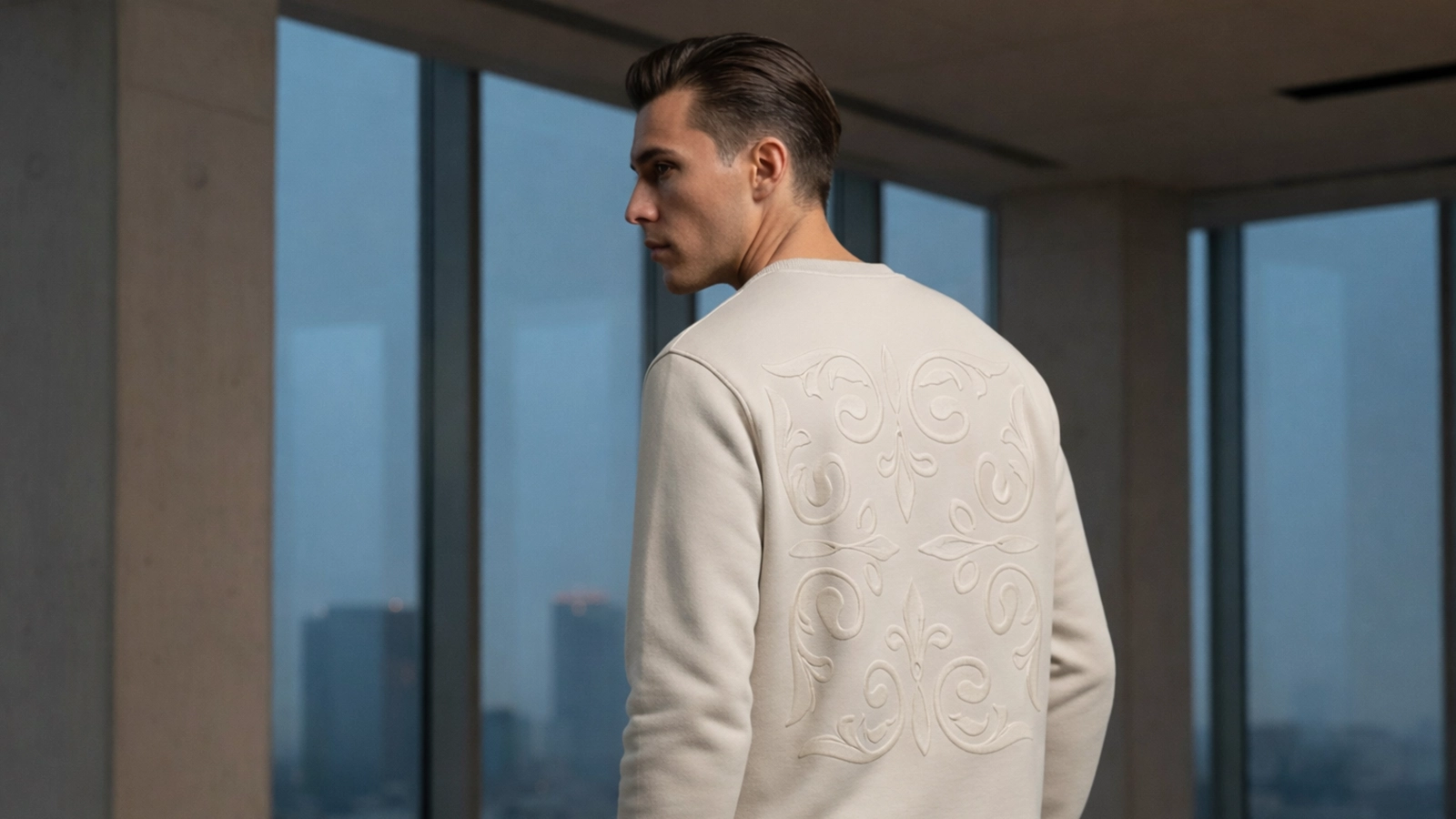 Hombre joven posando de espaldas con una sudadera color tierra con bordado al tono de la marca Faaia.