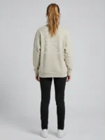 Mujer joven posando de espaldas a la cámara con una sudadera color tierra con bordado ornamental al tono marca Faaia.