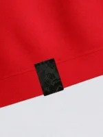 Etiqueta de tela damasco negra al tono sobre polo pique de color rojo.