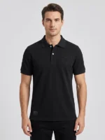 Hombre joven posando con un polo piqué de color negro con un bordado ornamental en el pecho