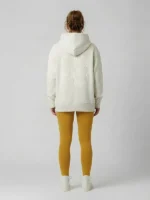 Mujer joven posando con sudadera de la marca Faaia moda con un bordado ornamental en color gris claro al tono.