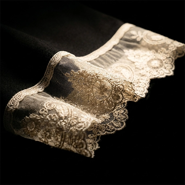 Zoom de puntilla valenciana aplicada en las mangas de una camiseta negra de la marca Faaia.