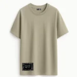 Camiseta oversize color tierra con parche textil con el logo de Faaia y tela fallera damasco en color negro.