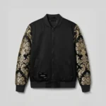 Chaqueta bomber negra con brocateles negro y dorado en las mangas.