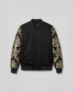 Chaqueta bomber negra con brocateles negro y dorado en las mangas.