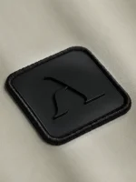 Etiqueta de micro inyección negra con el icono de la marca Faaia moda en relieve.