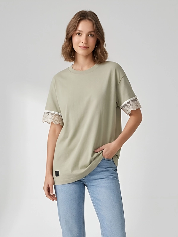 Mujer joven posando con camiseta oversize color tierra de la marca Faaia con puntilla valenciana en las mangas.