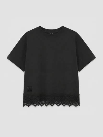 Vista frontal camiseta marca Faaia de color negro con corte crop para mujer y con puntilla valenciana insertada en el bajo.