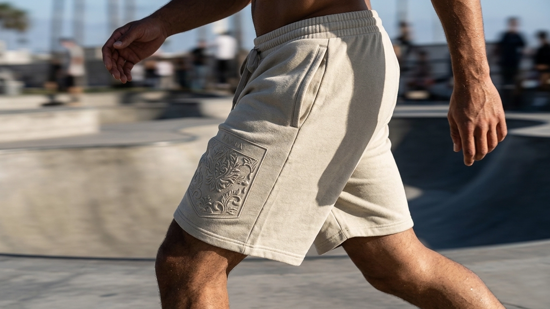 Hombre joven andando con pantalon corto de color beige y bordado tono sobre tono de la marca Faaia.