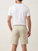 Hombre joven posando de espaldas con un pantalón corto de color beige de la marca Faaia.