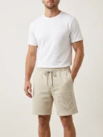 Hombre joven modelo posando con pantalon corto en color tierra de la marca Faia moda