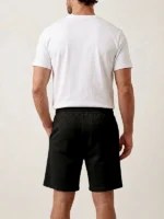 Hombre joven posando como modelo con pantalón negro corto de la marca Faaia.