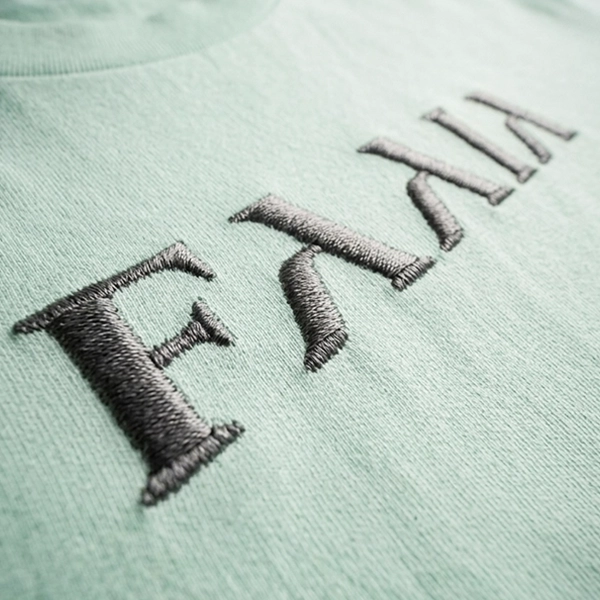 Logotipo Faaia bordado en el pecho de una camiseta verde agua.