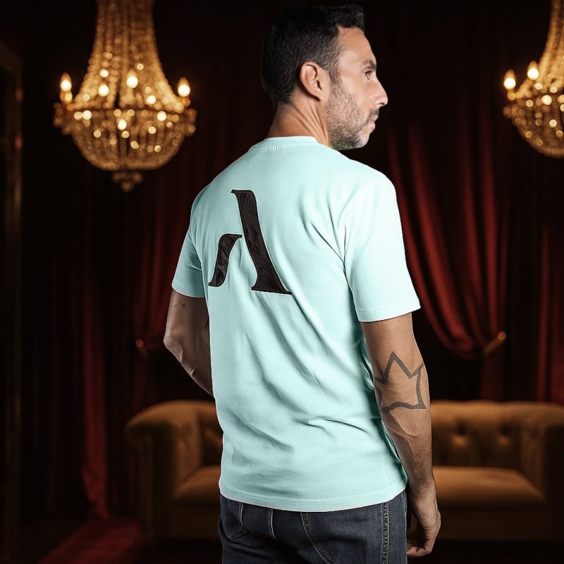 Hombre de espaldas con la camiseta turquesa de faaia en una lujosa sala con un sofá chester y candelabros