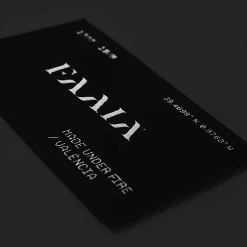 Parche textil negro con el logo de la marca de ropa Faaia sobre fondo gris oscuro